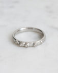 Silver ring with small diamonds on a light gray background