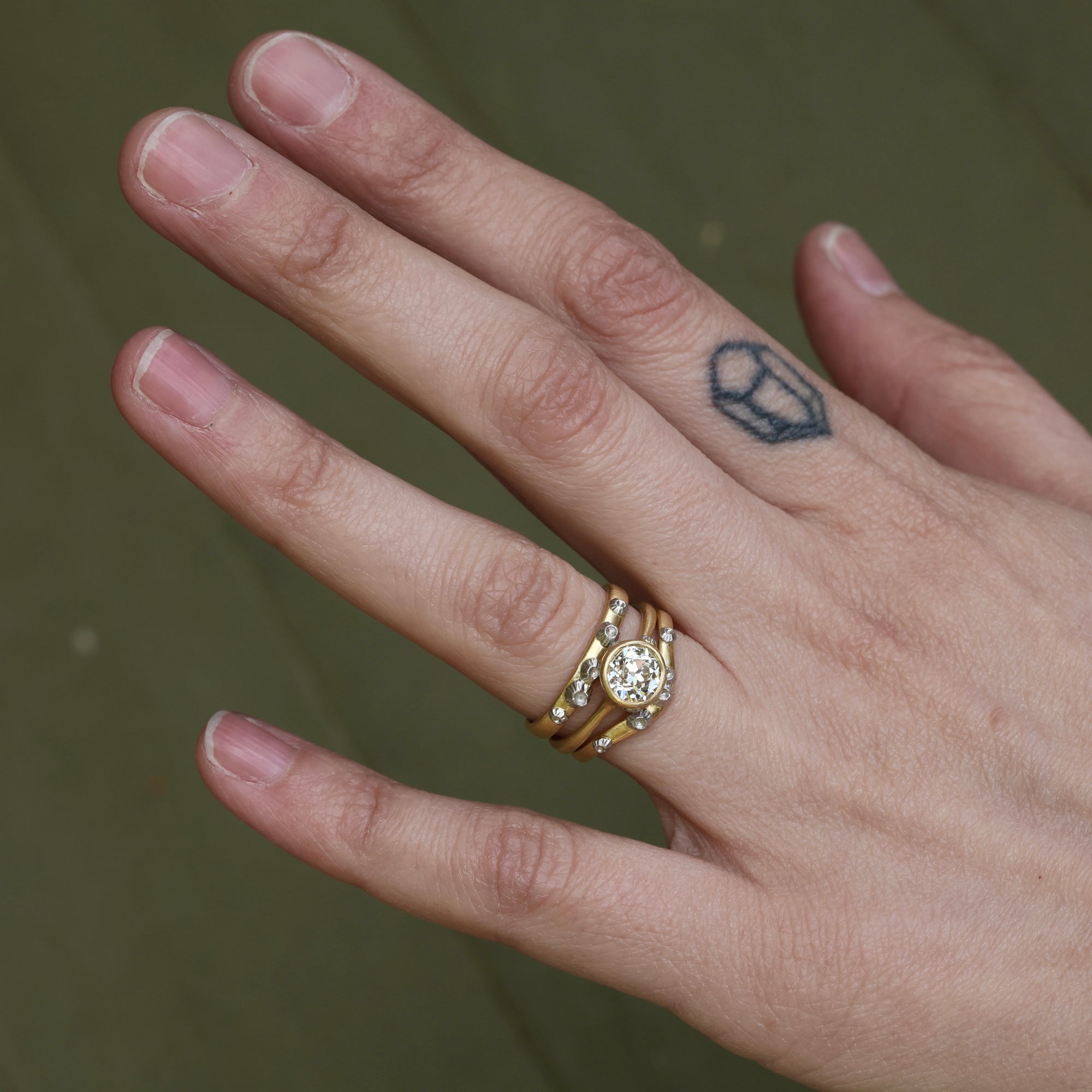 Hand wearing diamond ring with two bands surrounding it 