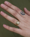 Hand wearing diamond ring with two bands surrounding it 