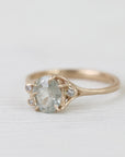 Gold ring with a pear-shaped white sapphire on a light fabric background