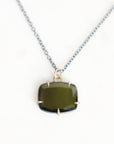 A silver chain necklace with a cushion-cut dark green gemstone pendant in a prong setting, displayed on a clean white background.