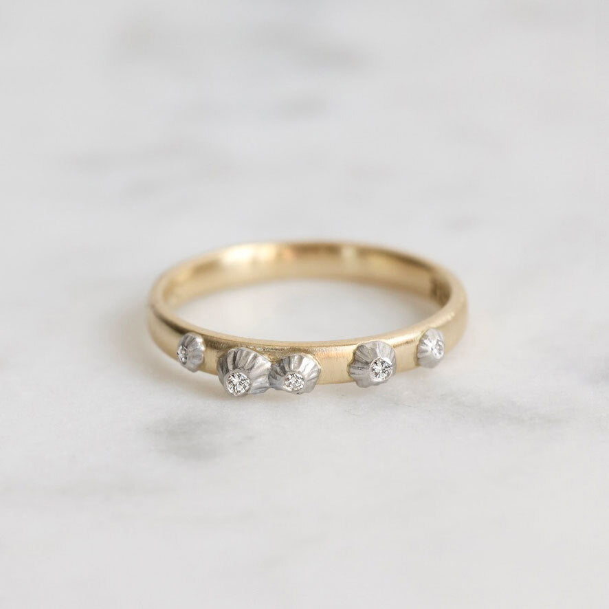Gold ring with barnacles on a light gray background