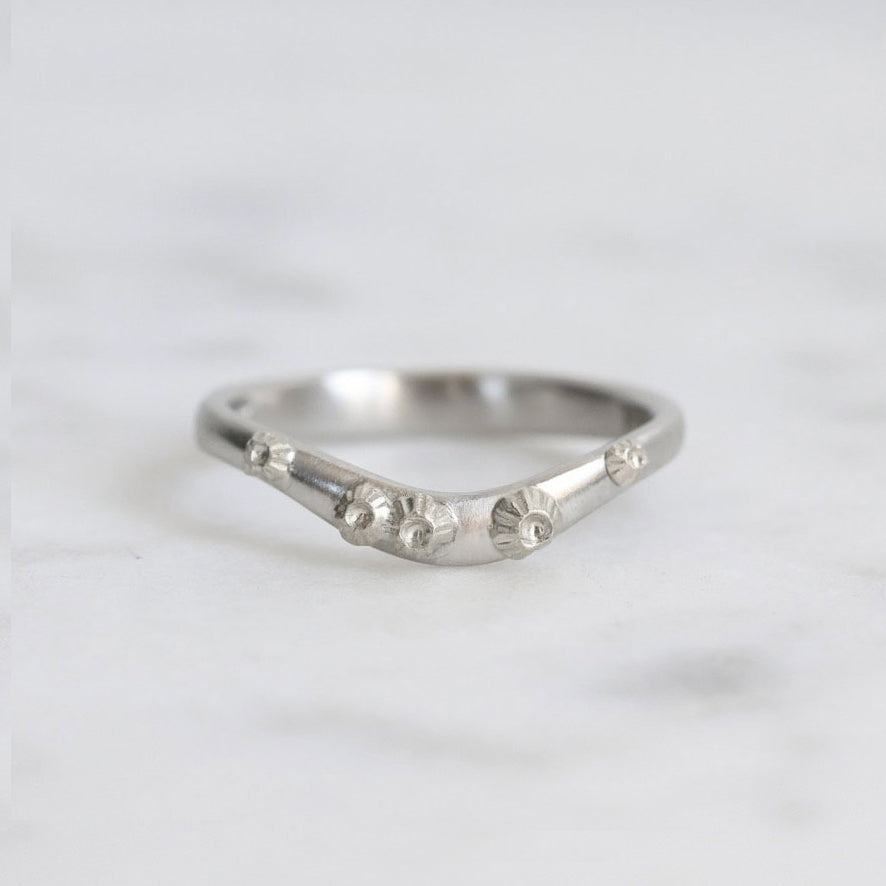 Silver ring with textured design on a white background