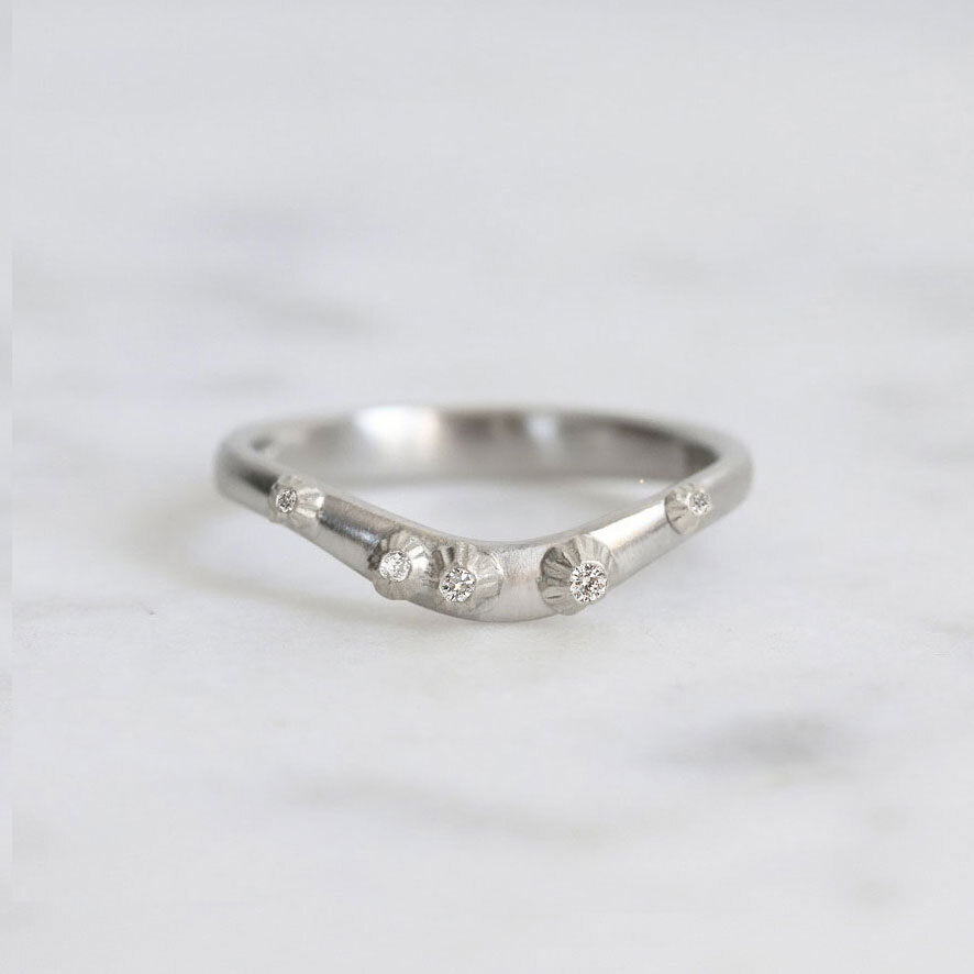Silver ring with small diamonds on a light gray background