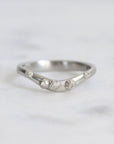 Silver ring with small diamonds on a light gray background