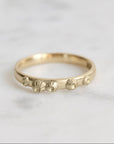 Gold ring with barnacle designs on a light gray background