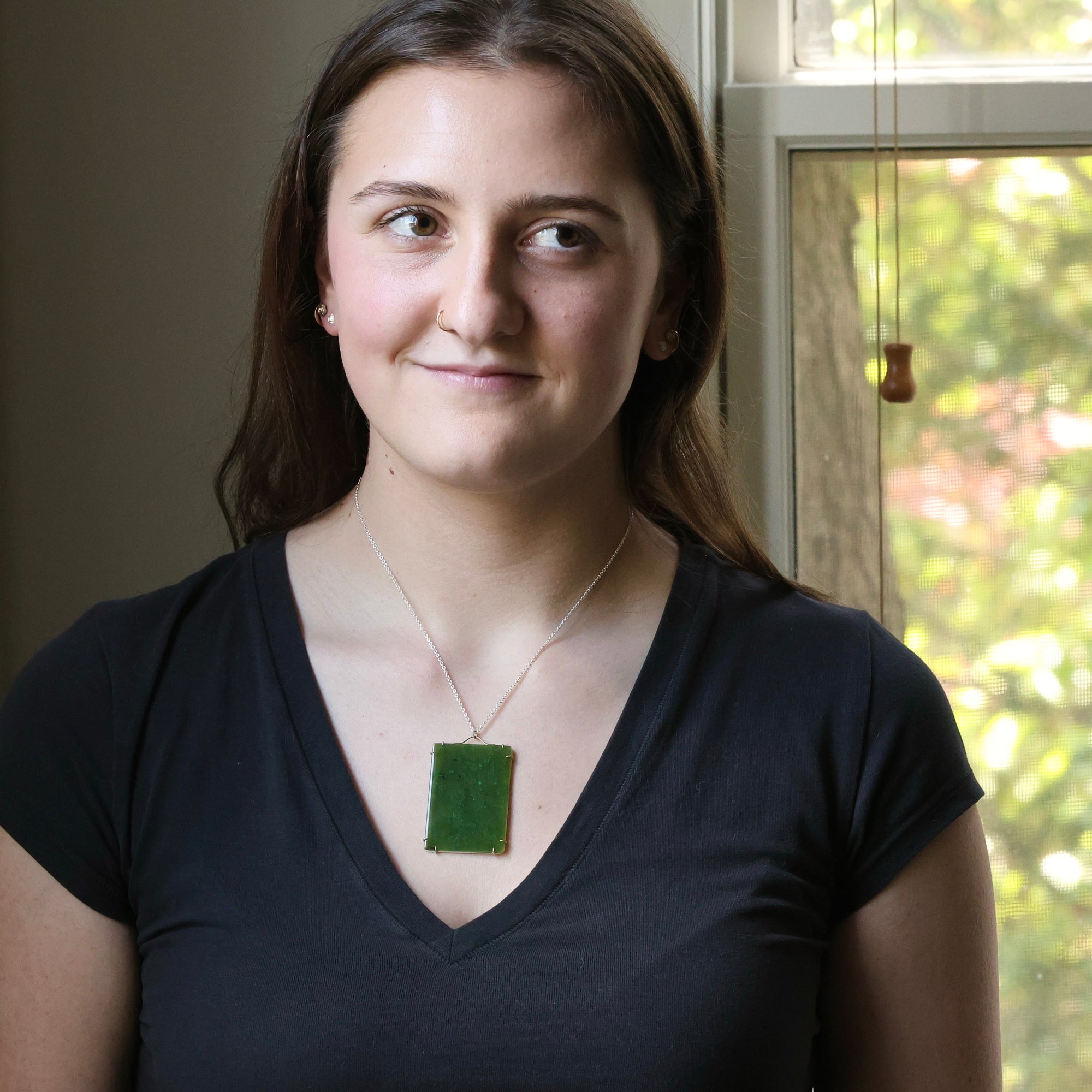Large green rectangular stone pendant on woman's neck
