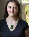 Large green rectangular stone pendant on woman's neck