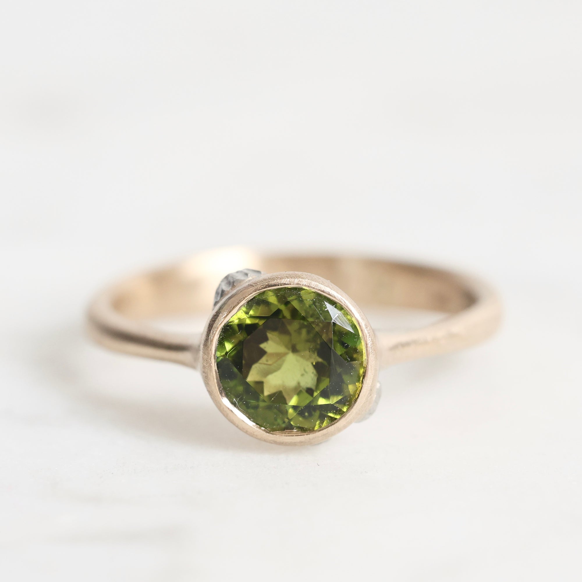 Gold ring with a green gemstone on a white background