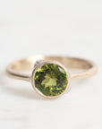 Gold ring with a green gemstone on a white background