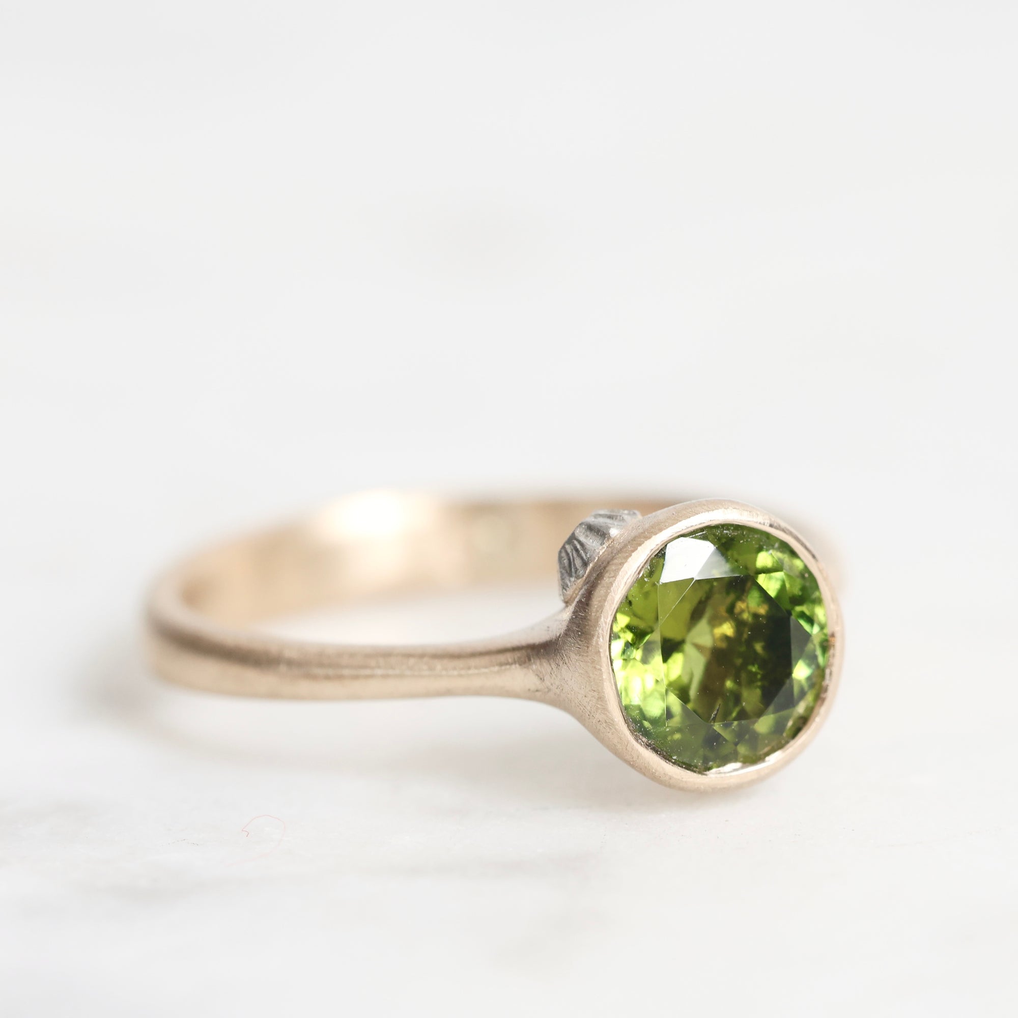 Gold ring with a green gemstone on a white background