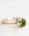 Gold ring with a green gemstone on a white background