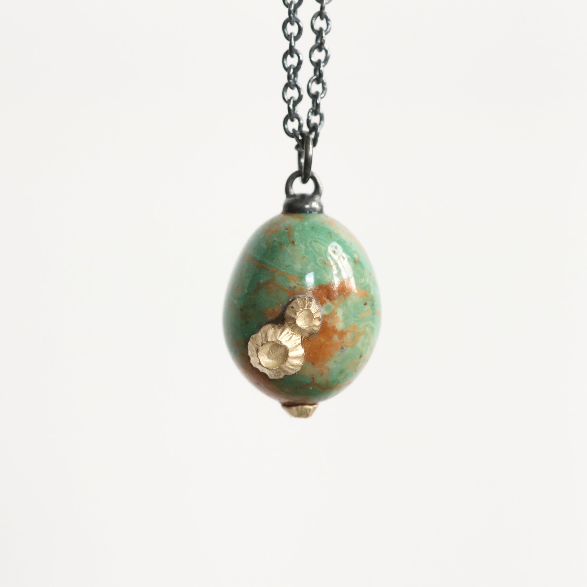 Necklace with a green marbled pendant and gold accent on a white background