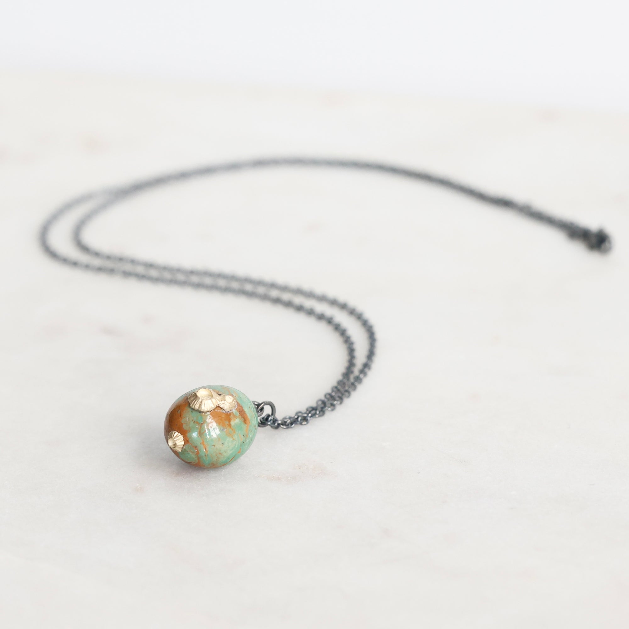 Necklace with a round, multicolored pendant on a white background