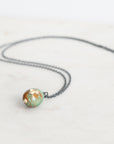 Necklace with a round, multicolored pendant on a white background