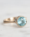 Gold ring with a blue gemstone on a light gray background