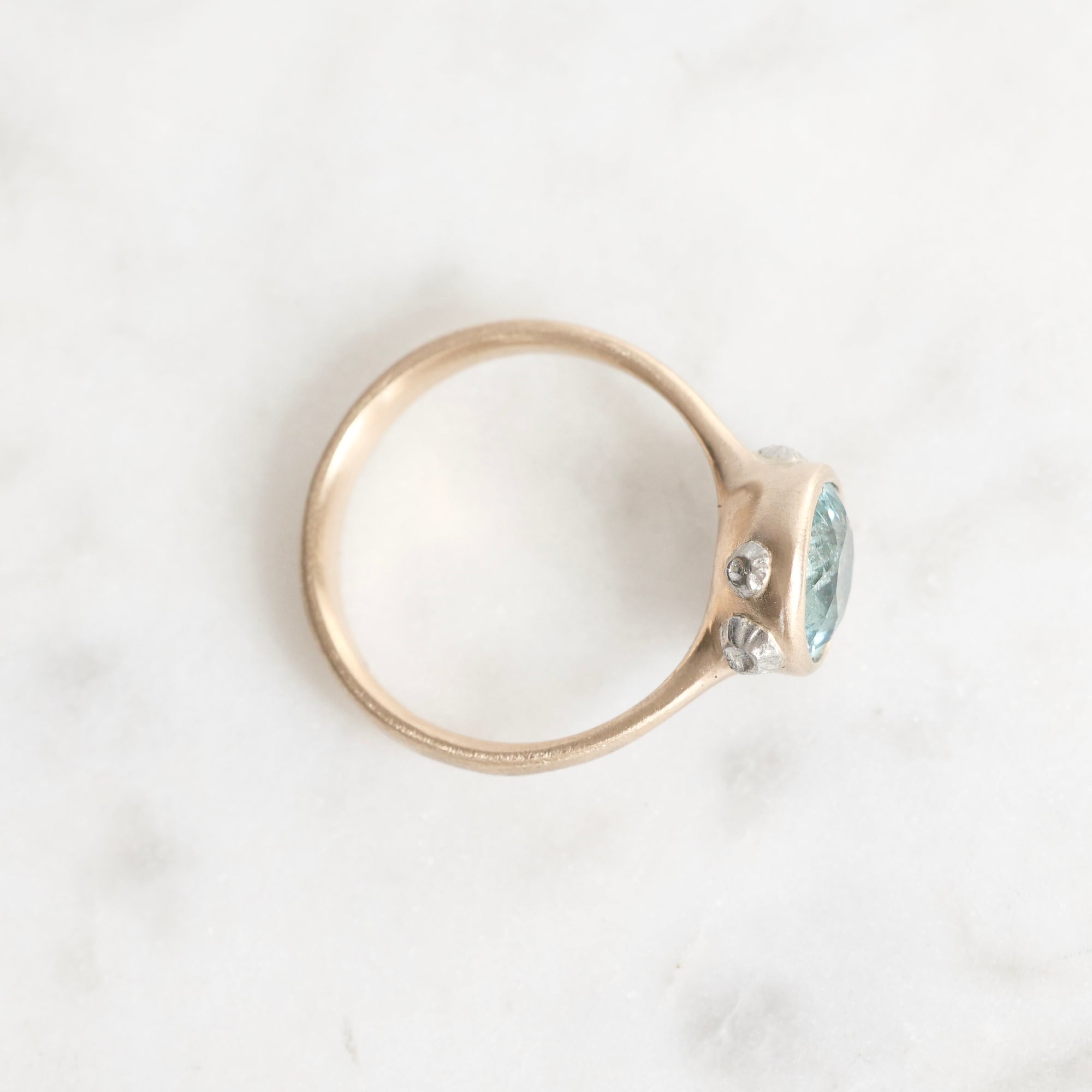 Gold ring with a blue gemstone on a white background