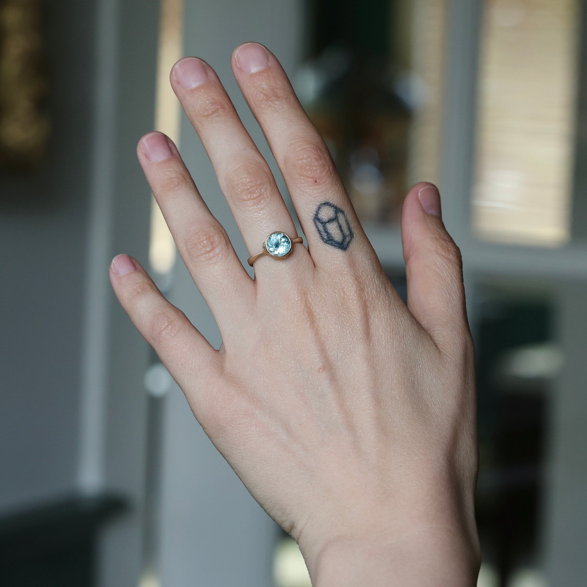 Hand with a ring and tattoo on a blurred background