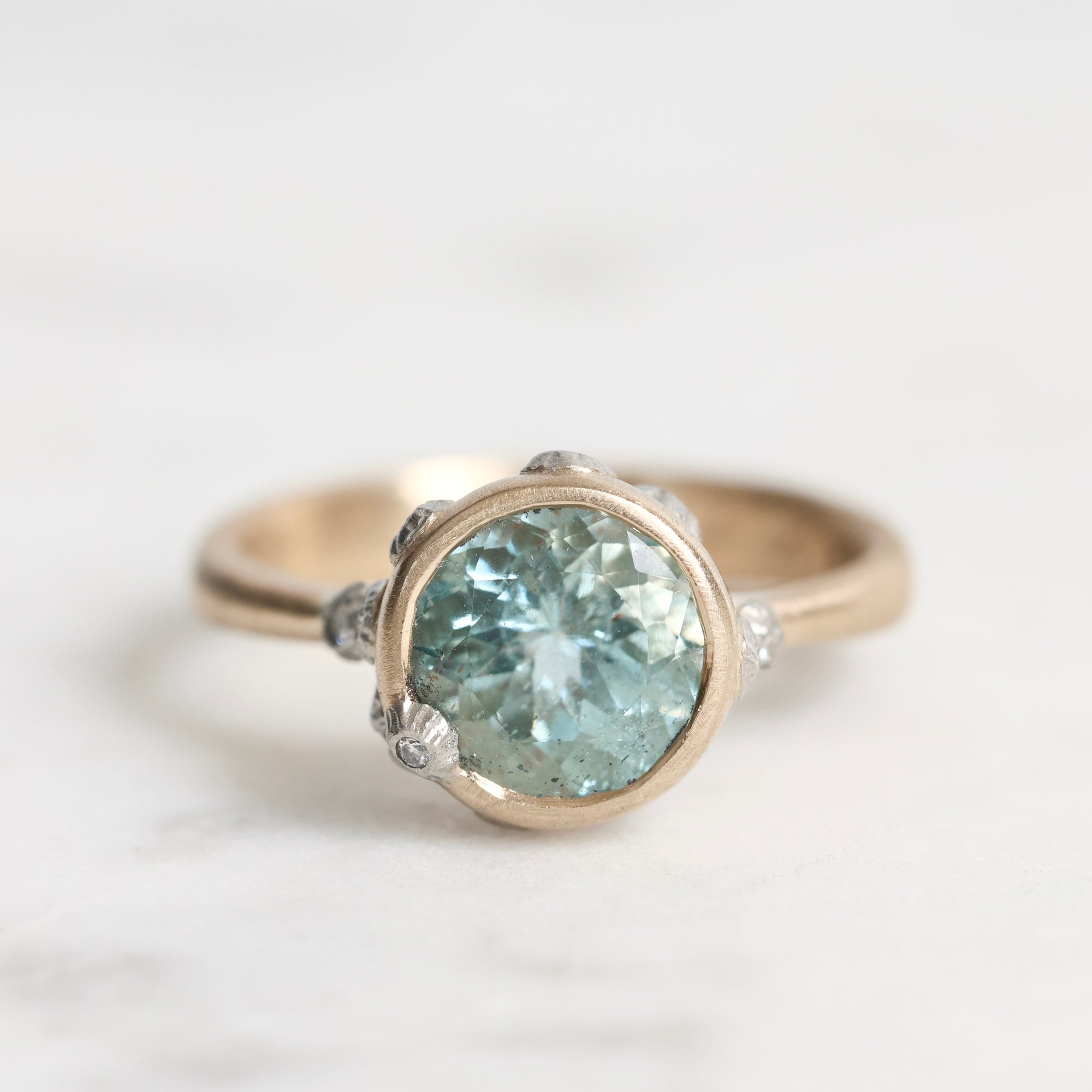 Gold ring with a blue gemstone on a light background