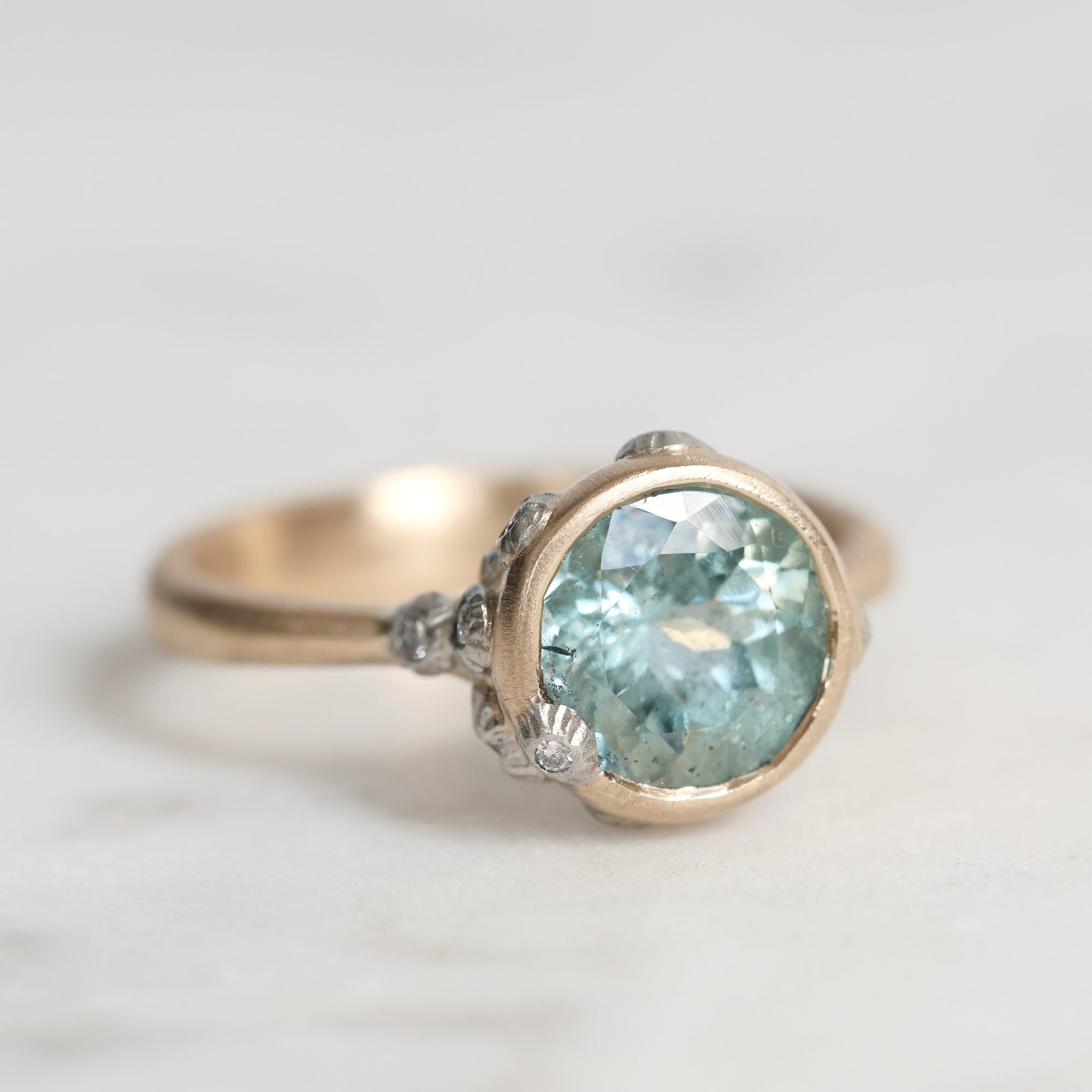 Gold ring with a large blue gemstone on a light gray background