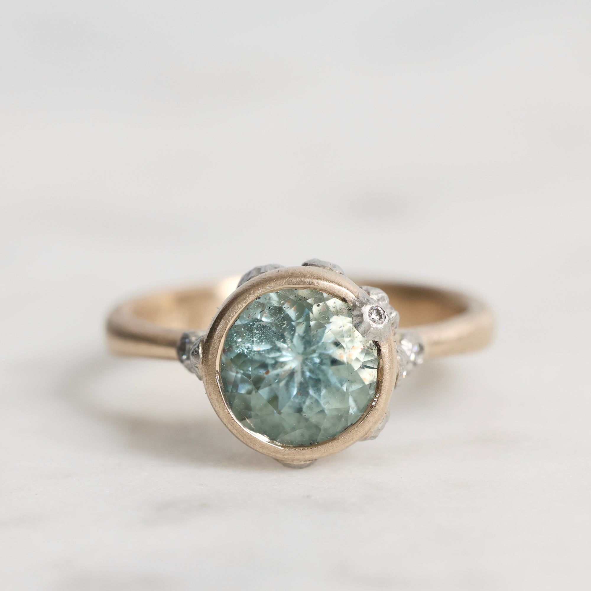 Ring with a green gemstone and silver setting on a light gray background
