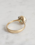 Gold ring with a green gemstone on a light gray background