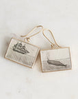 Pair of earrings with ship and whale illustrations on a light background