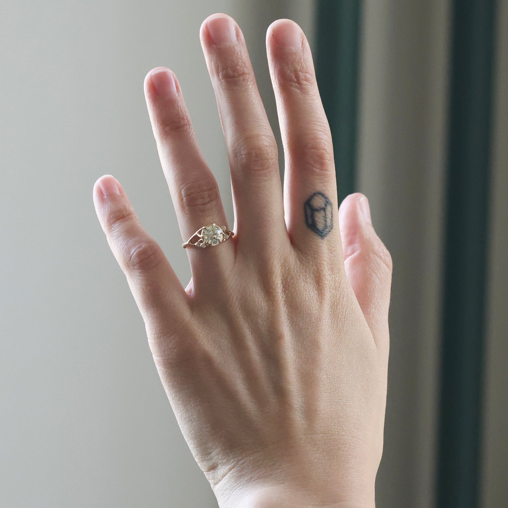 Hand with a diamond ring on a neutral background