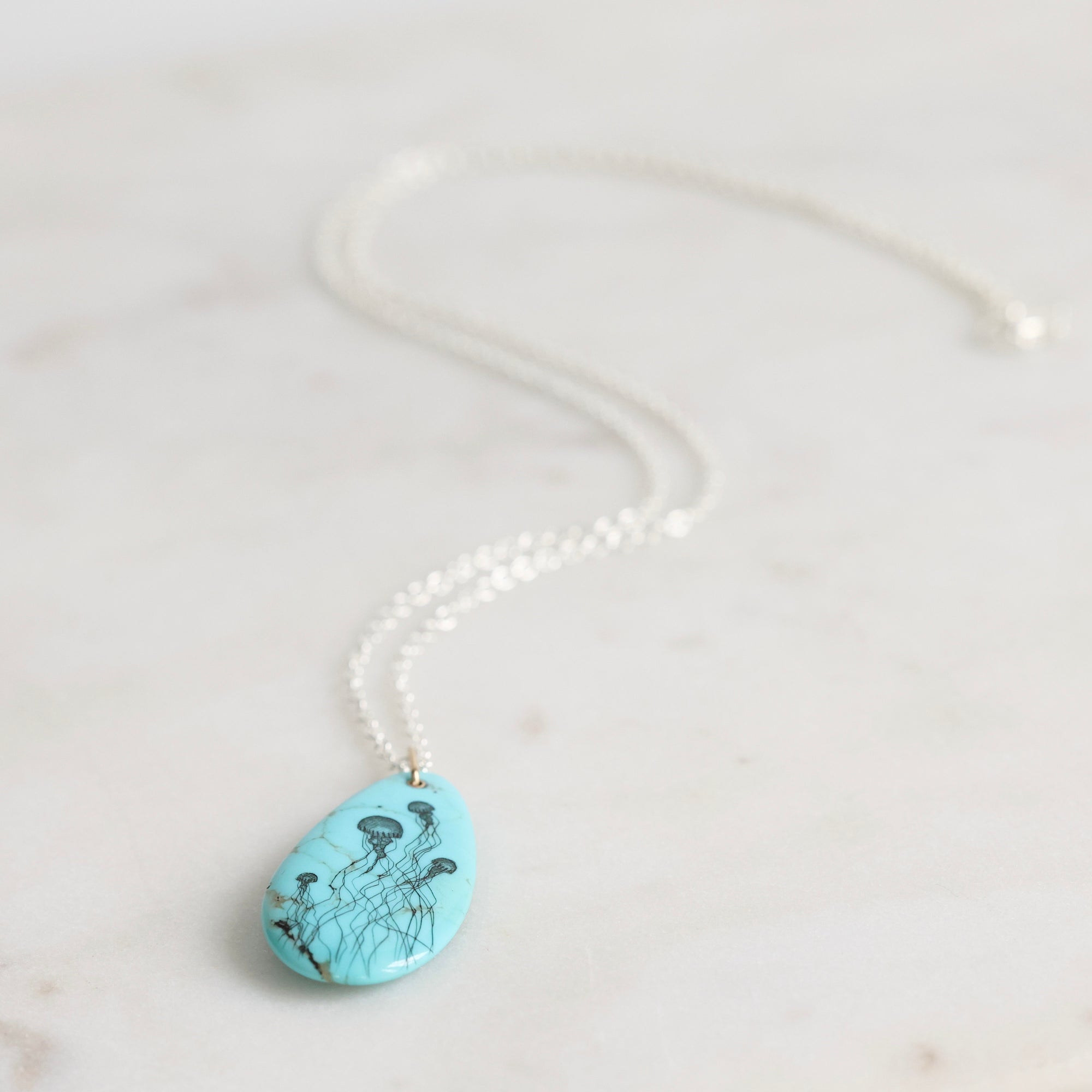 Turquoise pendant necklace on a white marble surface