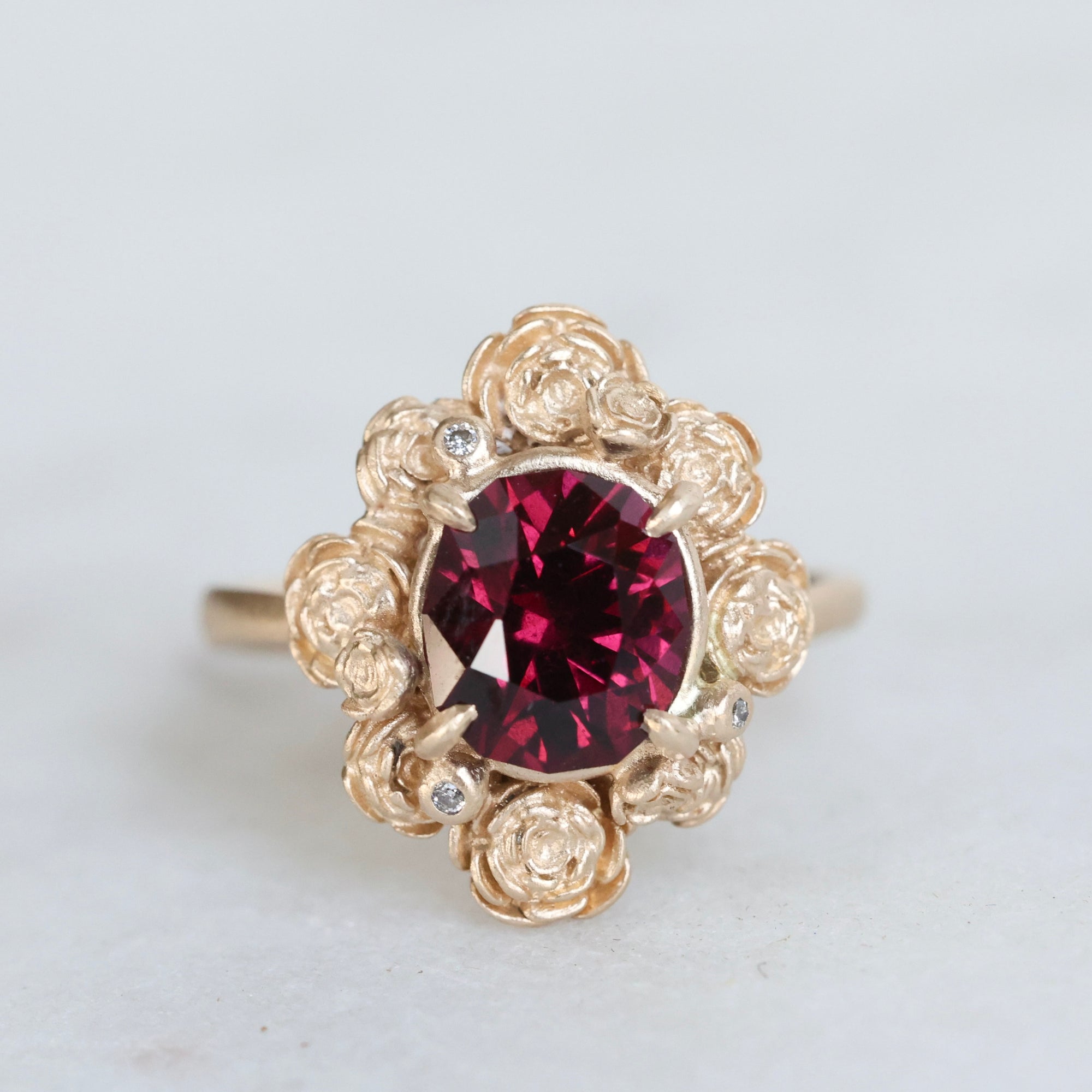 Gold ring with a red gemstone on a light gray background