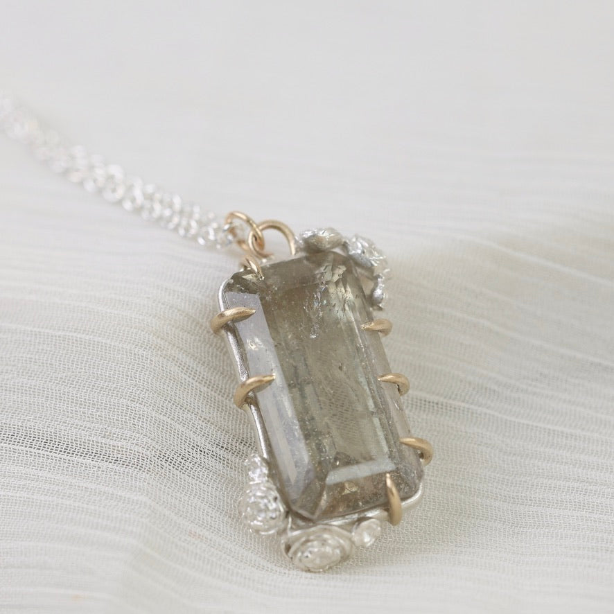 Necklace with a clear crystal pendant on a white fabric background