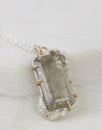 Necklace with a clear crystal pendant on a white fabric background