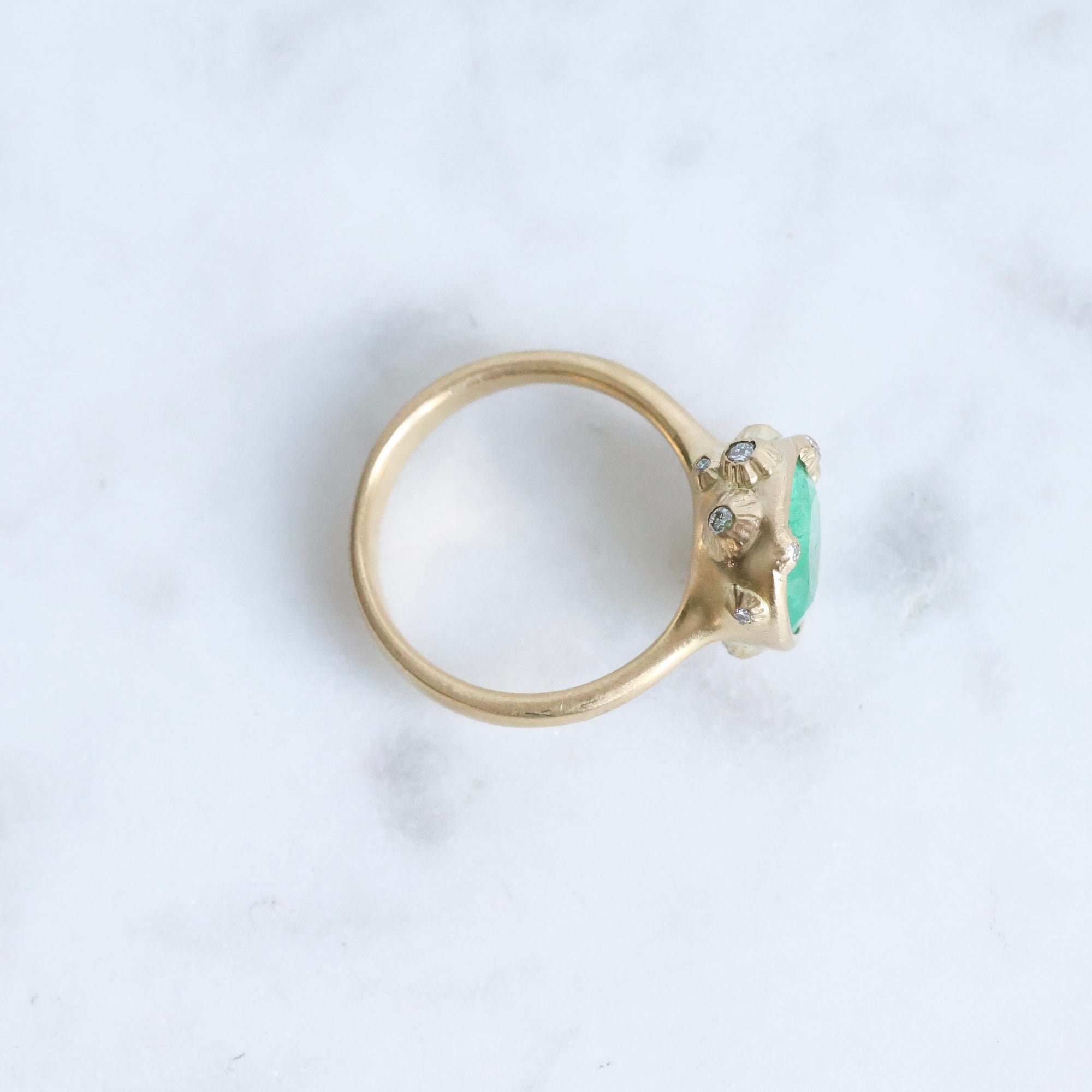 Large green gemstone ring surrounded by gold barnacles with diamonds 