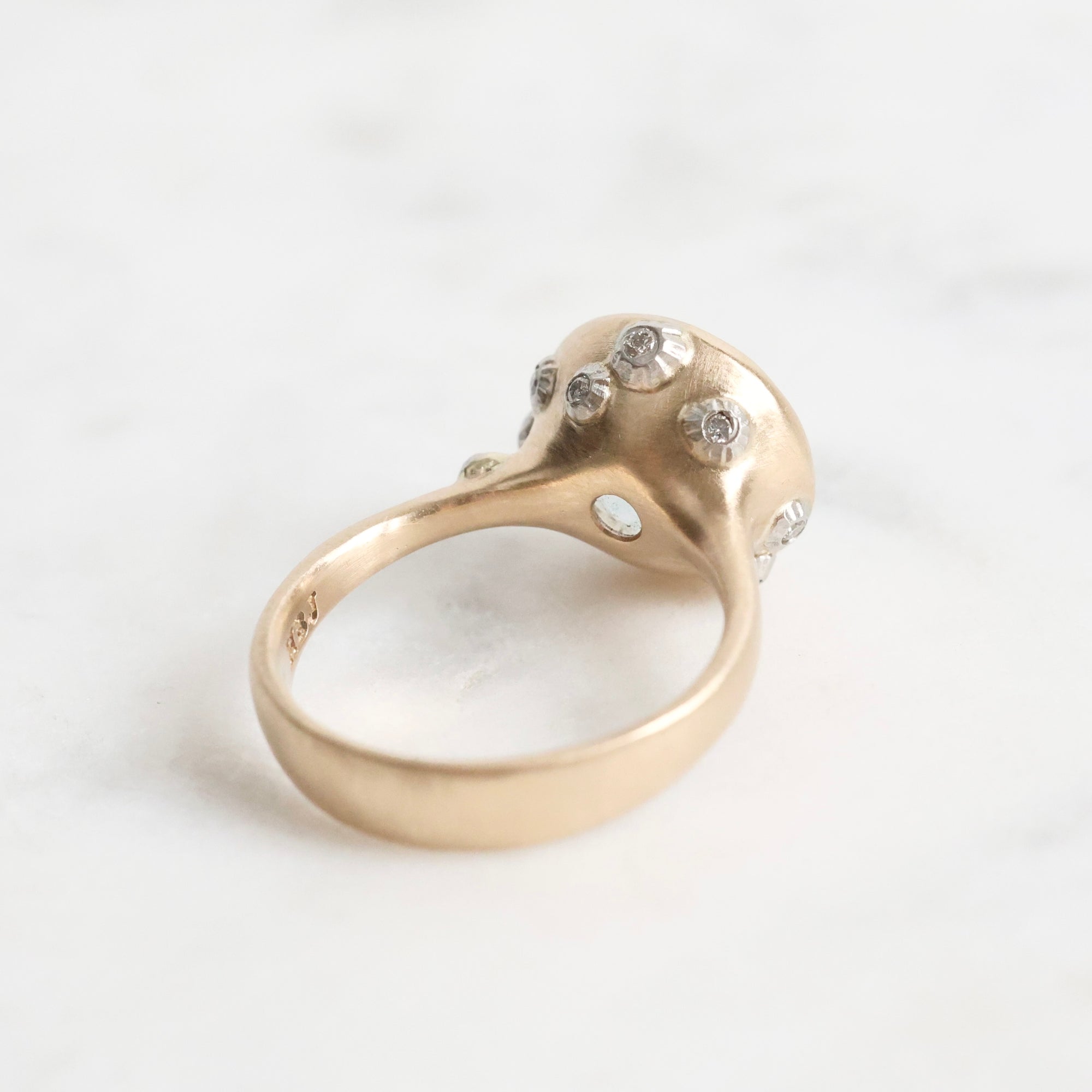 Gold ring with a large, faceted aquamarine stone on a light background