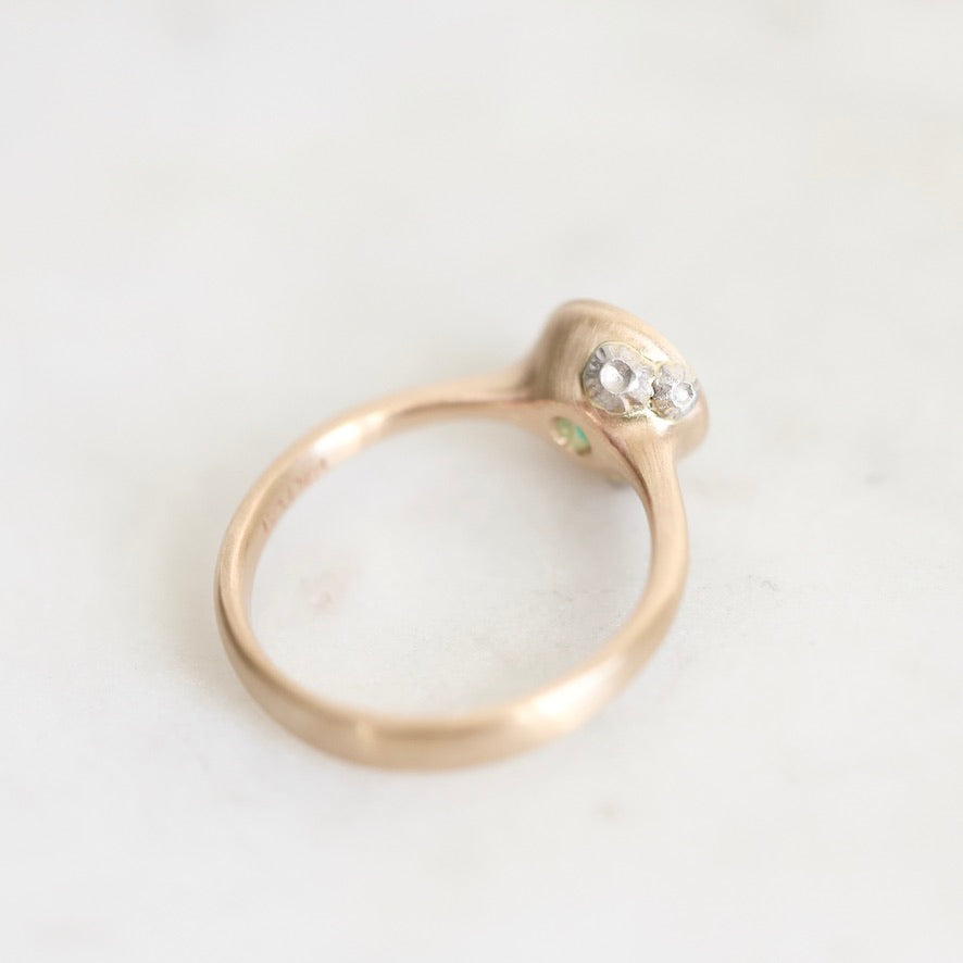 A gold ring with a small cluster of barnacles on a light, off-white marble surface.