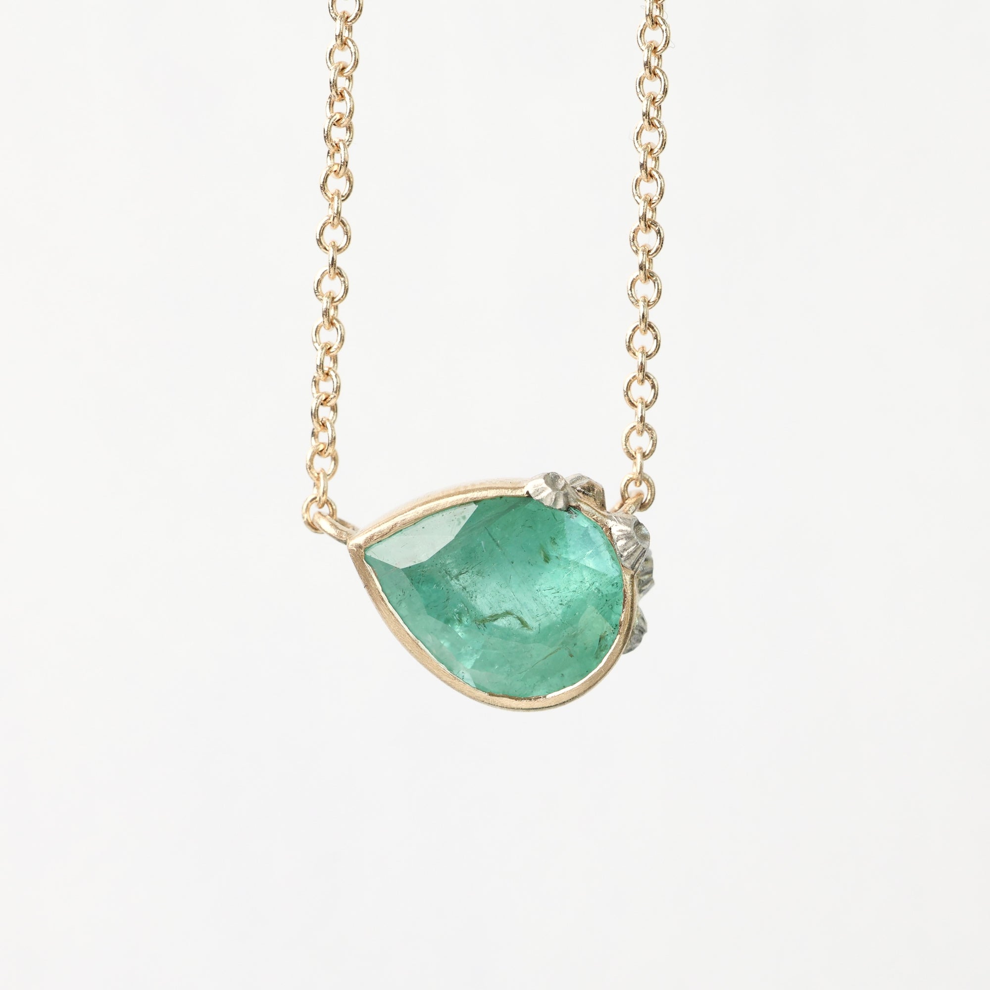 Necklace with a green teardrop pendant on a light gray background