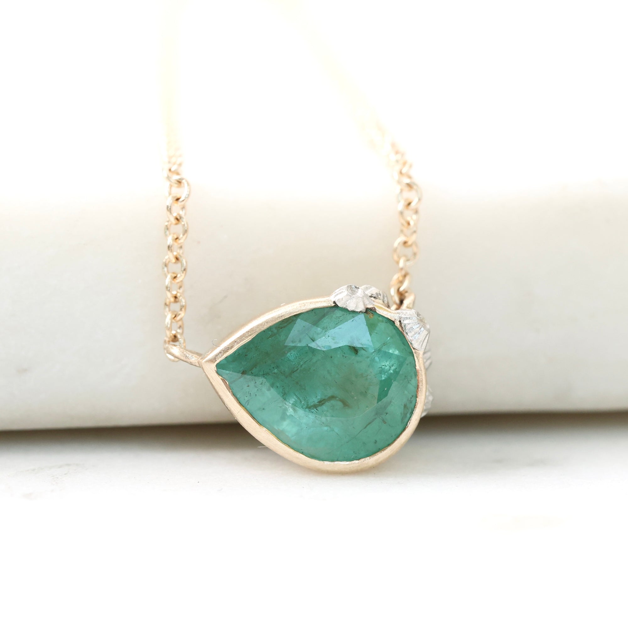 Teardrop-shaped green gemstone necklace on a white background