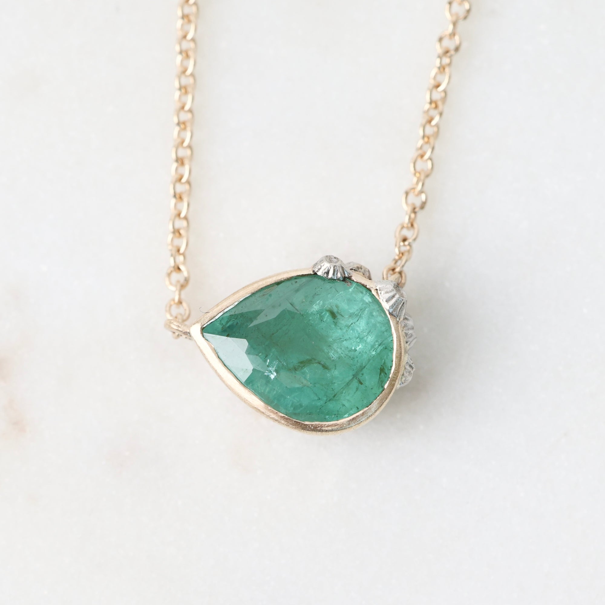 Necklace with a green teardrop pendant on a white background