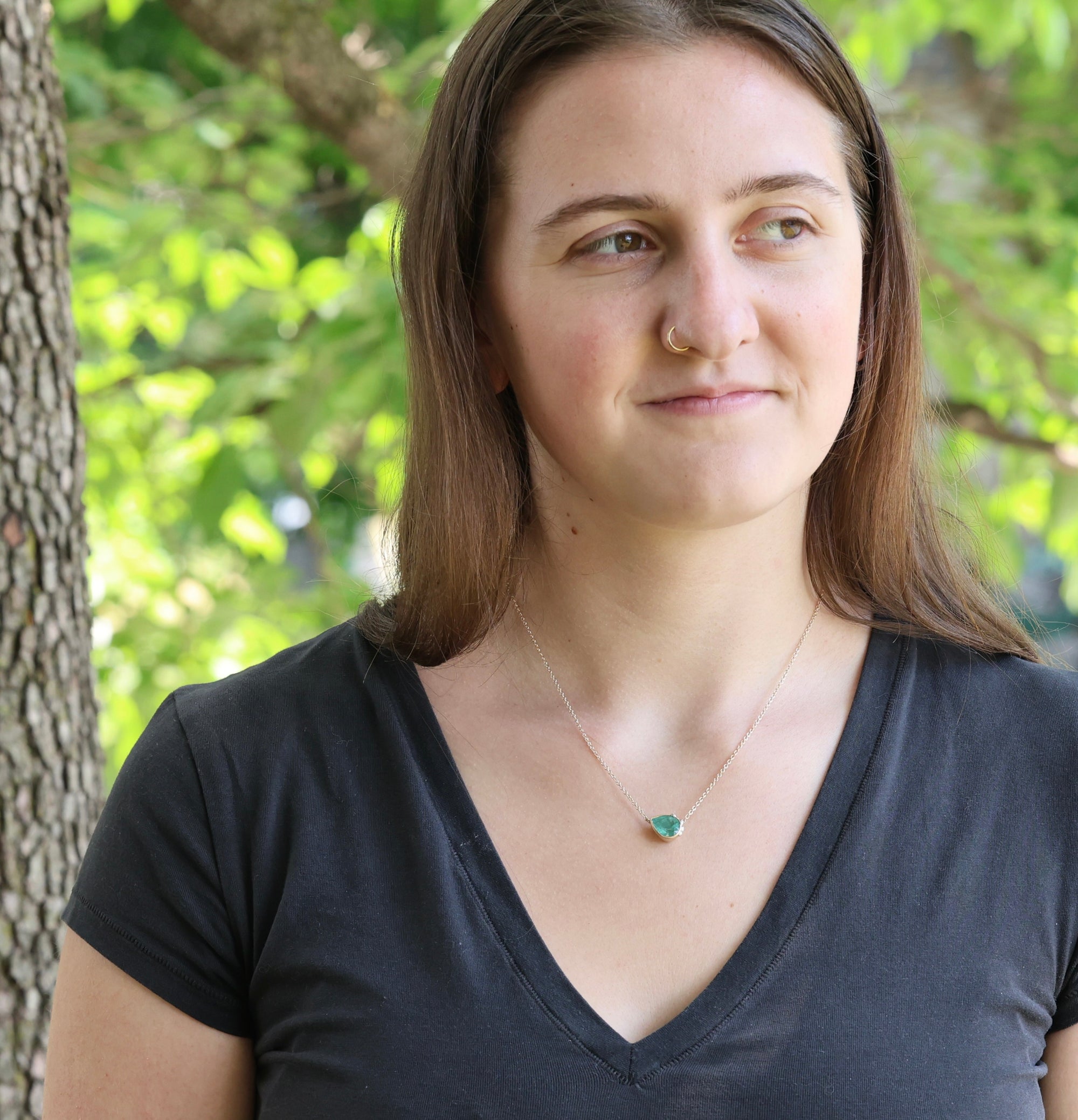 Woman wearing a black shirt with a green necklace in a natural setting