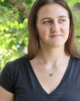 Woman wearing a black shirt with a green necklace in a natural setting