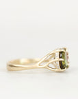 A yellow gold ring featuring a rectangular green gemstone in a prong setting with small clear accent stones, shown against a plain white background.