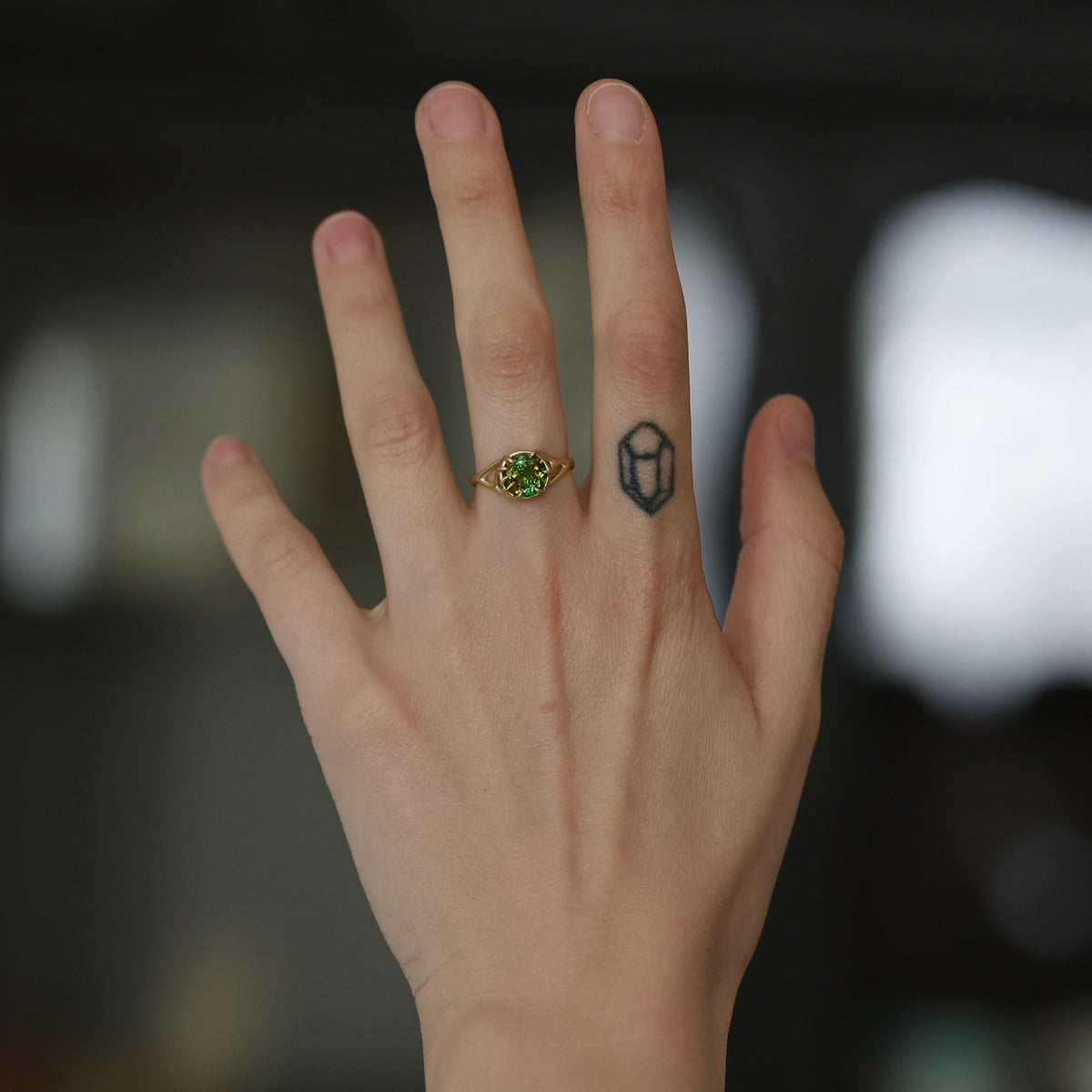 Hand wearing green gemstone ring. 