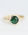 Green gemstone set in gold bezel with barnacle details