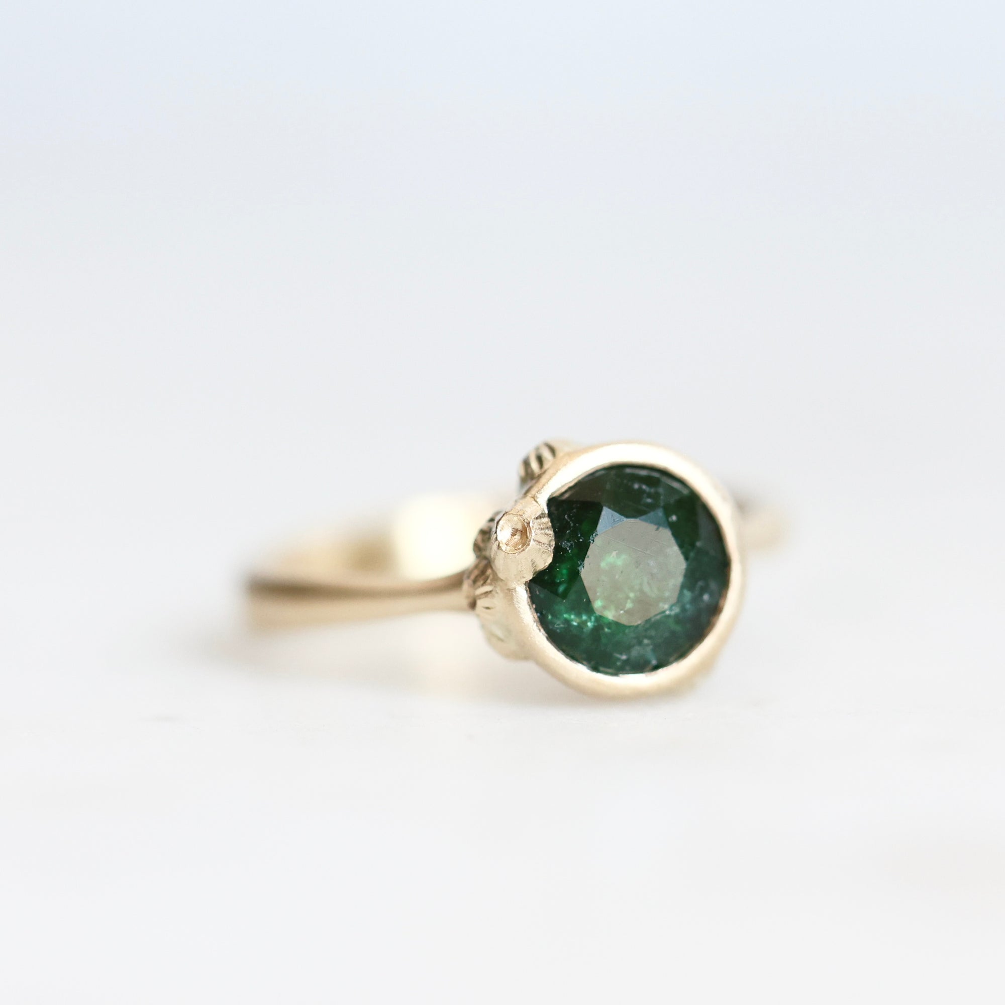 Green stone ring with gold bezel and barnacle accents 