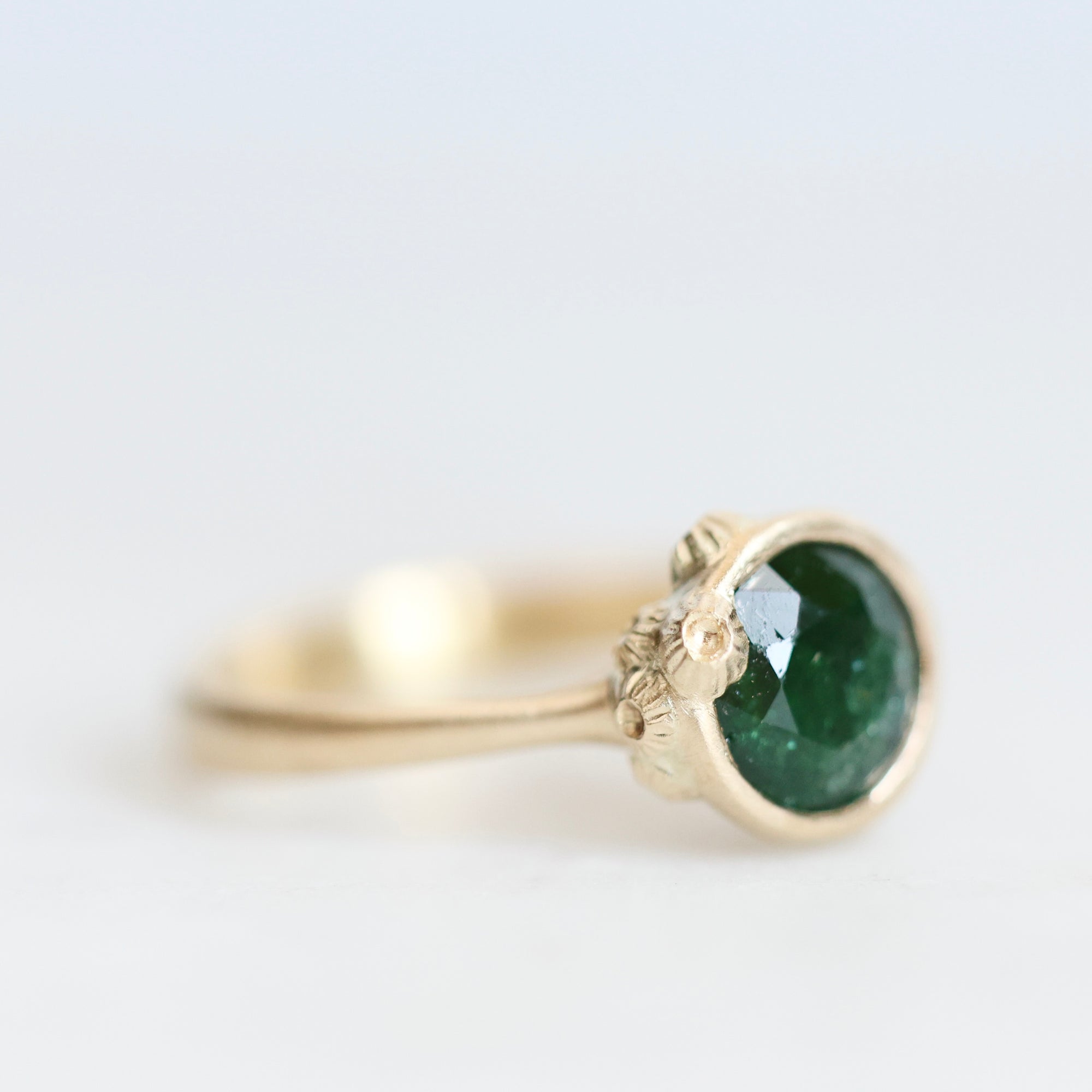 Side of gold Ruthie B. Ring with bright green stone. Clustered gold barnacles visible 