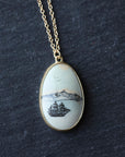 Close up of a necklace featuring a white stone with a ship engraving 