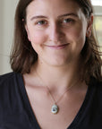Woman wearing necklace with an engraved ship 