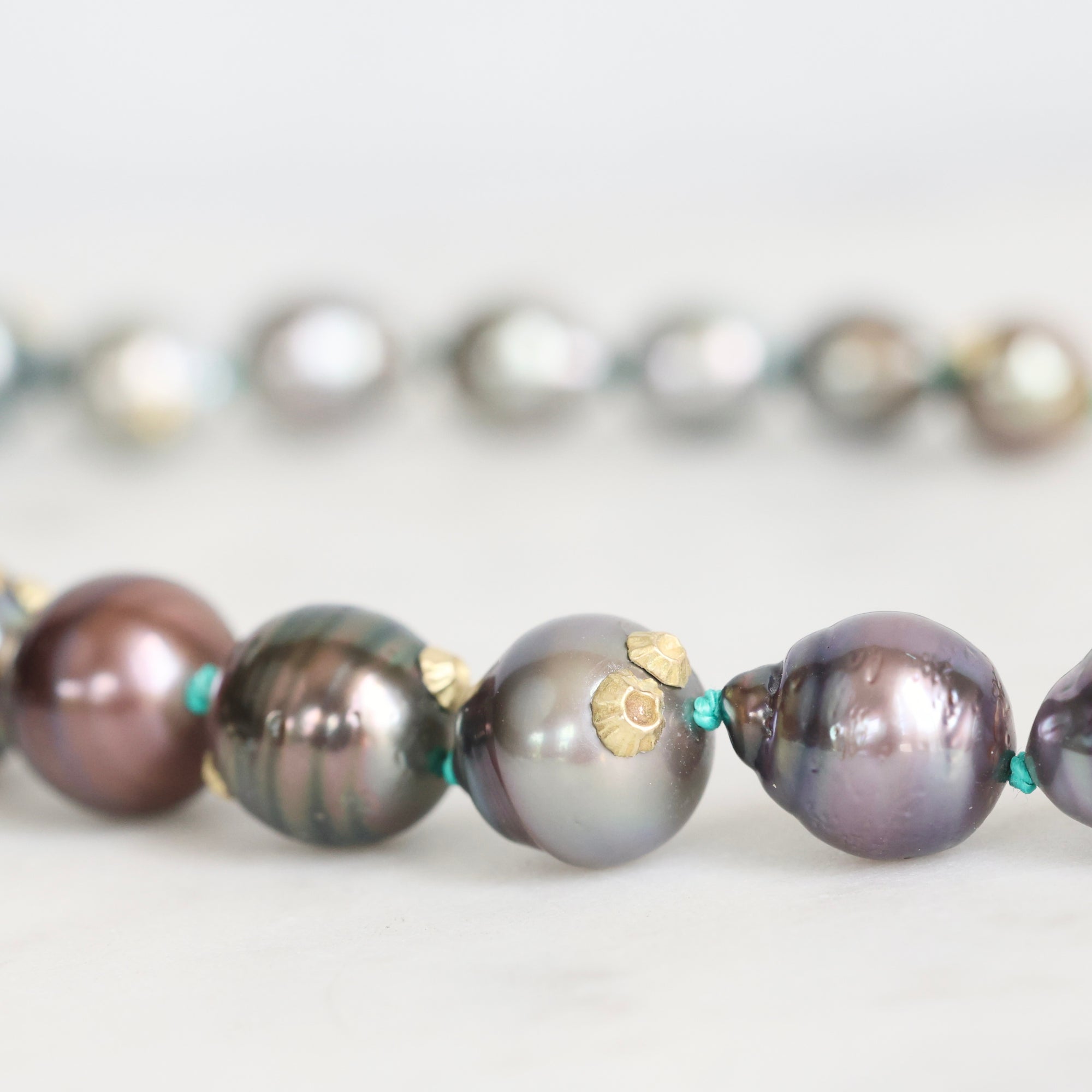 Close-up of a necklace with pearls and gold accents on a light background