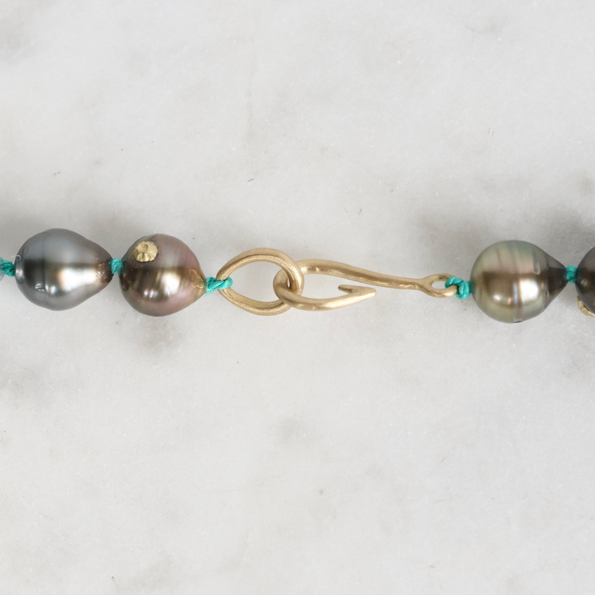 Pearl necklace with gold clasp on a light gray background