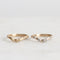 two gold curved rings, one with diamonds, on a light gray background